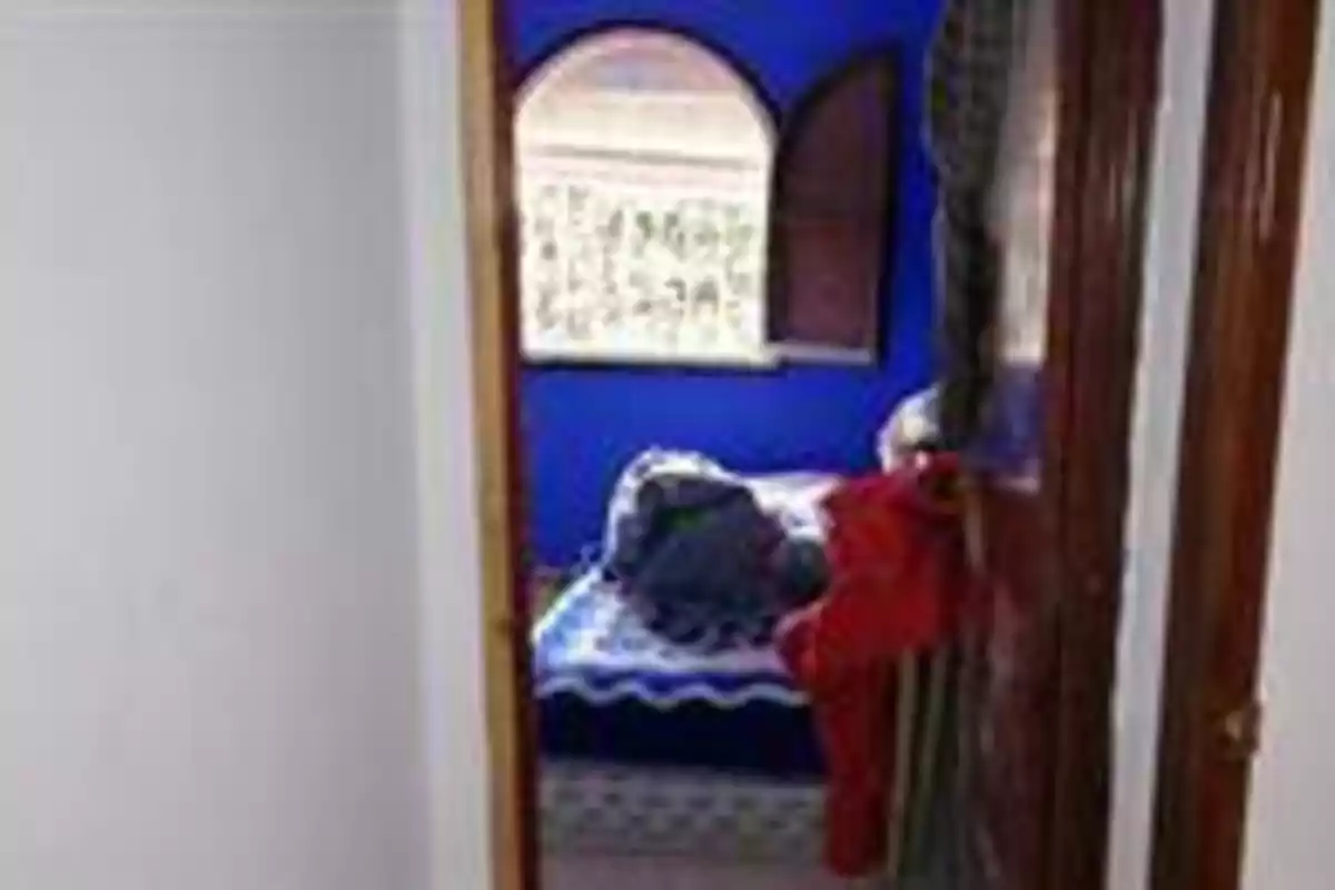 Habitación con paredes azules, una cama y una ventana con cortinas.