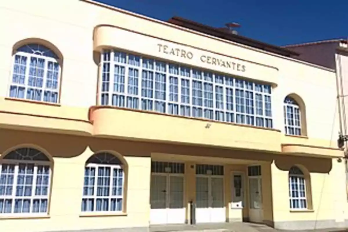 Fachada del Teatro Cervantes con grandes ventanas y puertas de vidrio.