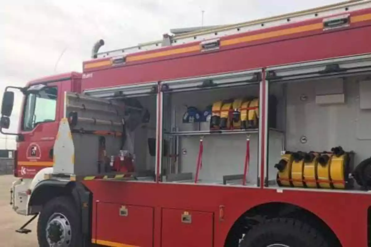 Camión de bomberos rojo con compartimentos abiertos mostrando equipo de emergencia.