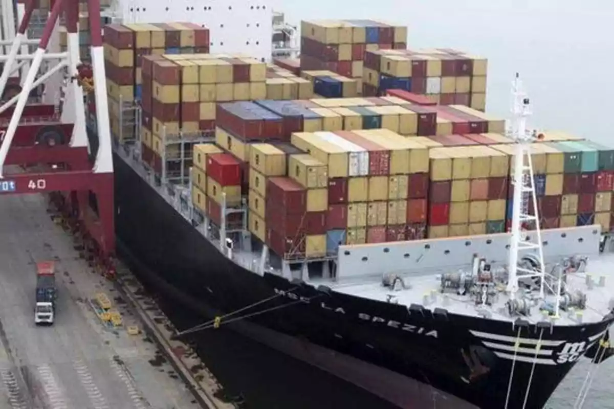 Un barco de carga lleno de contenedores atracado en un puerto.