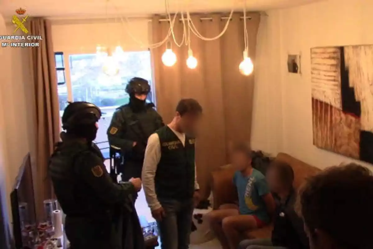 Agentes de la Guardia Civil realizan una operación en el interior de una vivienda, donde varias personas están siendo detenidas.