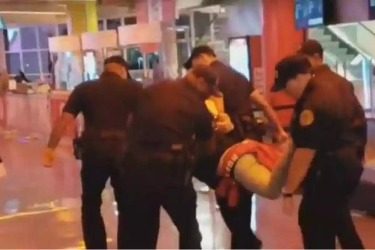 Un grupo de policías está deteniendo a una persona en un lugar público.