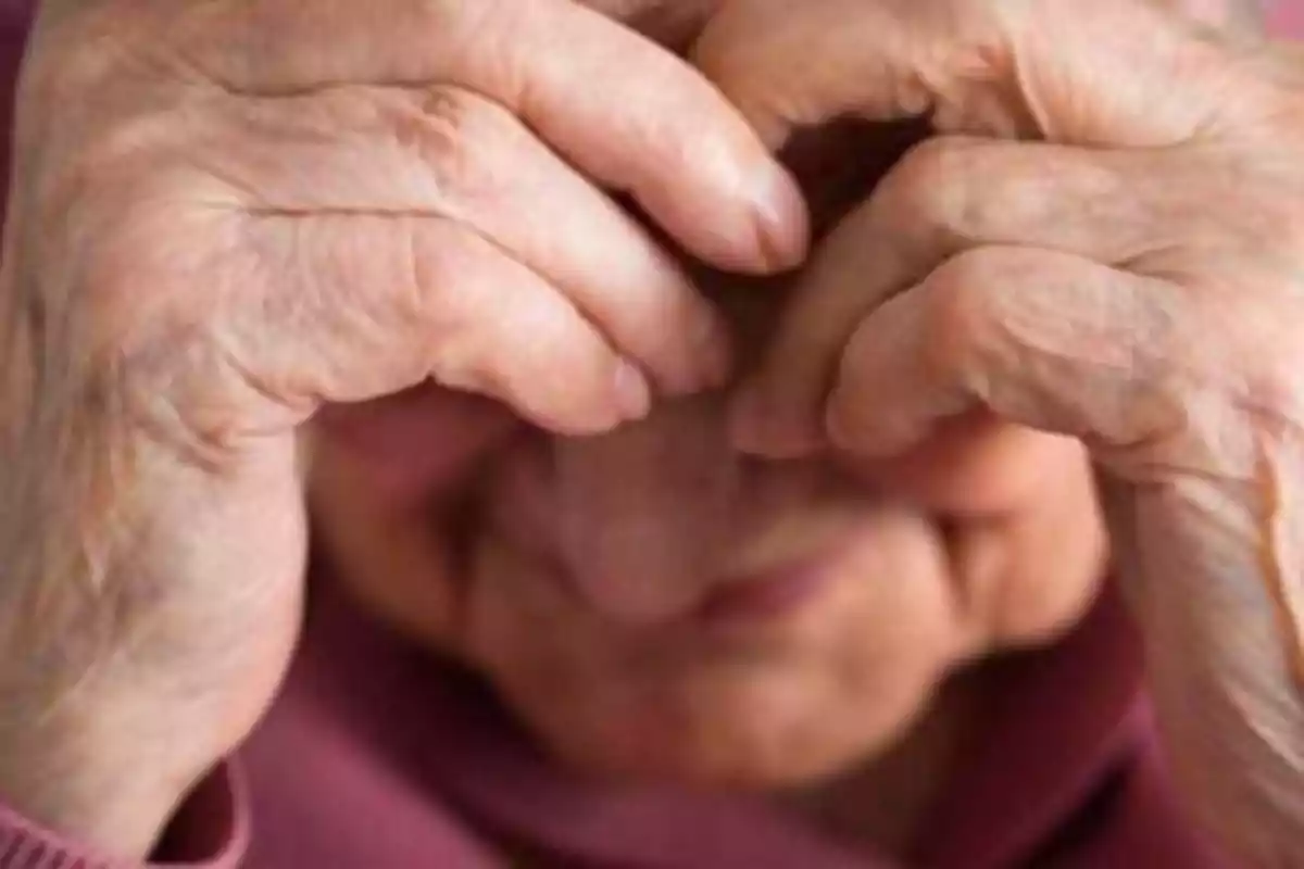 Persona mayor con las manos cubriendo su rostro.