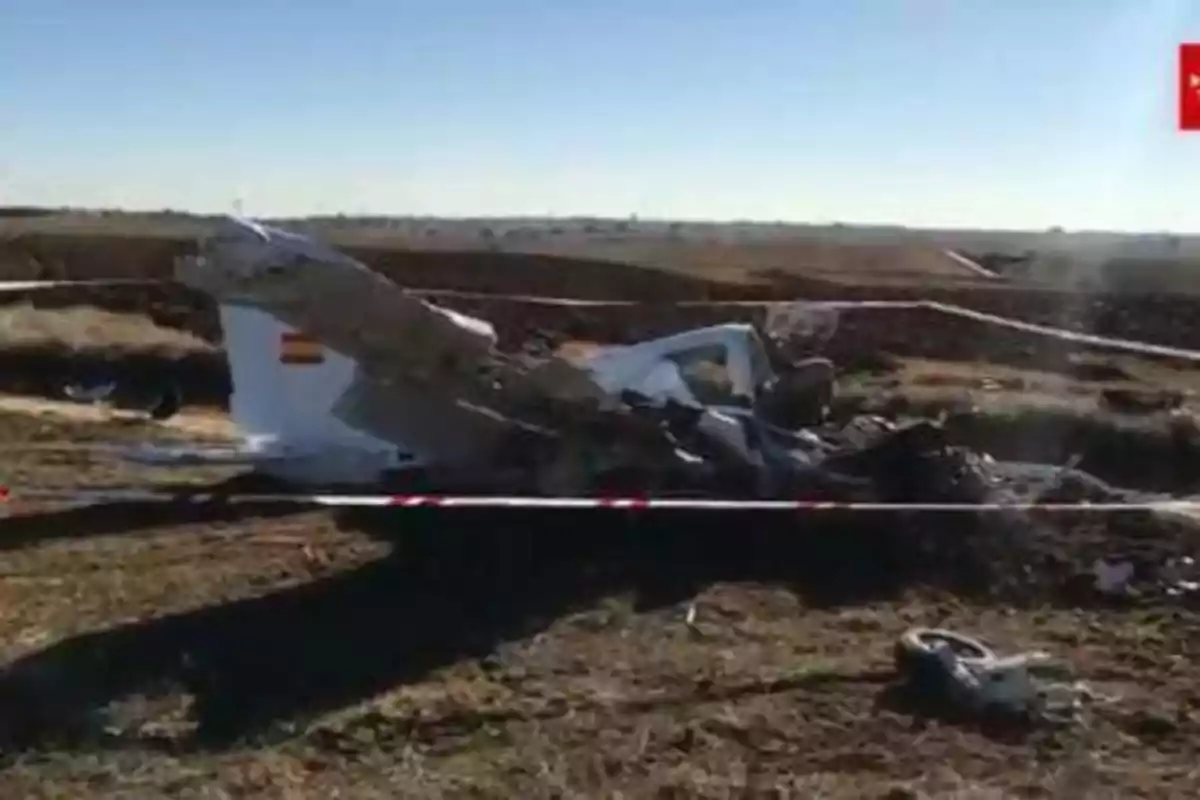 Restos de un avión accidentado en un campo, rodeados por una cinta de seguridad.