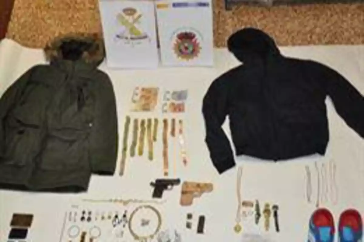 Imagen que muestra dos chaquetas, una verde y otra negra, junto a varios objetos como relojes, joyas, billetes, dos pistolas, documentos y un par de zapatos rojos.