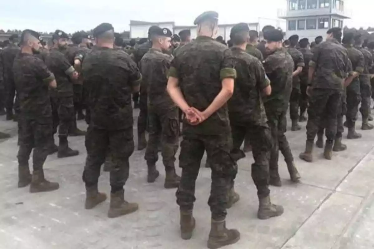 Un grupo de soldados en uniforme militar se encuentra de pie en formación en una base militar.