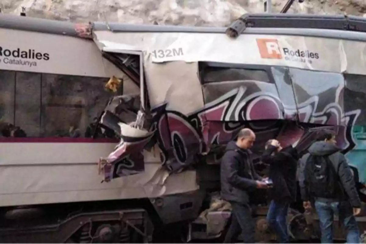 Un tren de Rodalies de Catalunya con daños visibles en su estructura y personas alrededor.