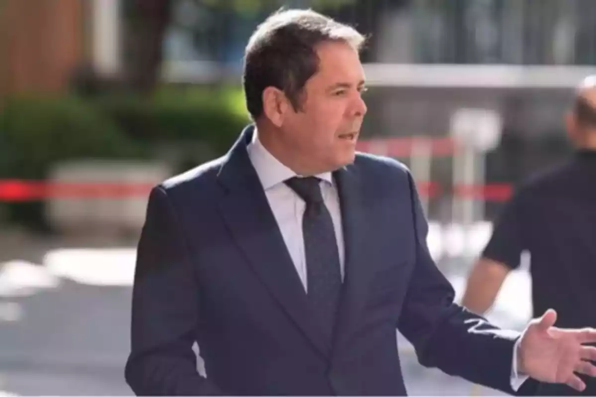 Un hombre con traje oscuro y corbata está de pie al aire libre en un entorno urbano. Un hombre con traje oscuro y corbata está de pie al aire libre en un entorno urbano.