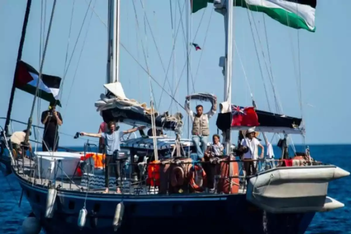 Un grupo de personas navega en un velero decorado con banderas mientras disfrutan del mar en un día soleado Un grupo de personas navega en un velero decorado con banderas mientras disfrutan del mar en un día soleado