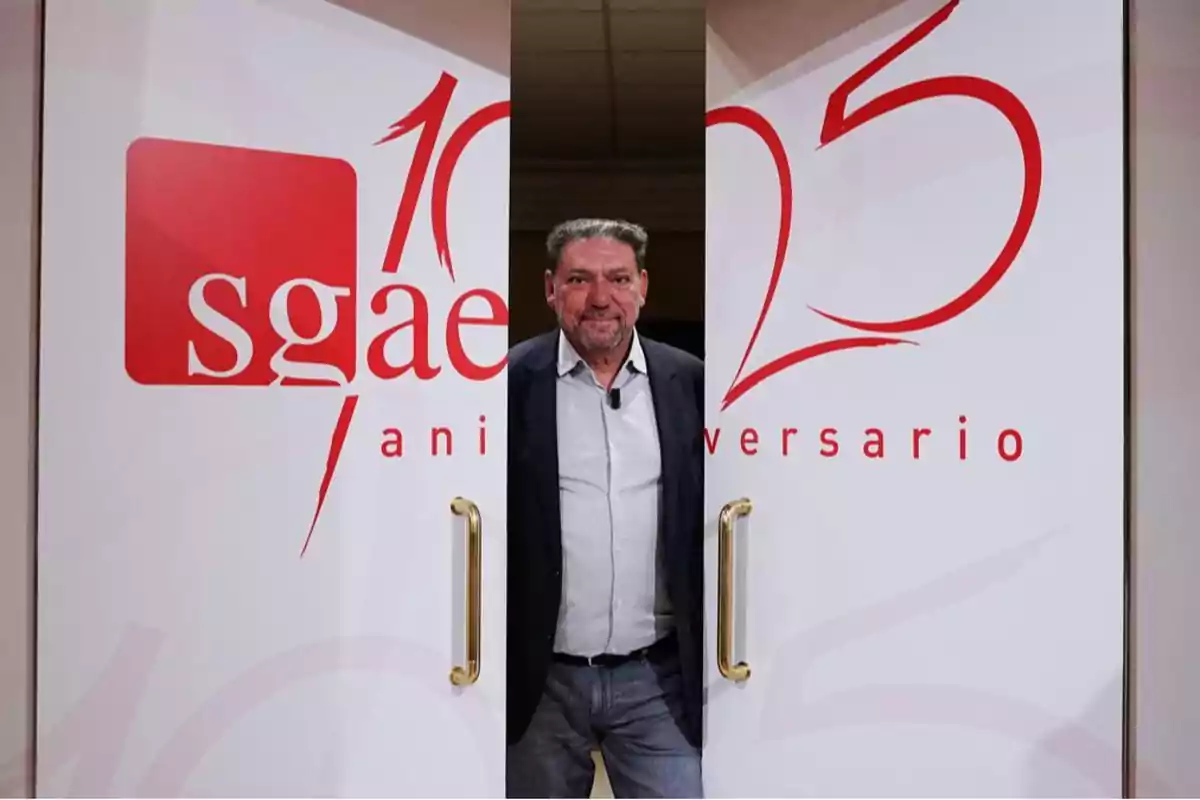 Un hombre de pie en el centro de dos puertas blancas con el logotipo de SGAE y el número 125 en rojo.