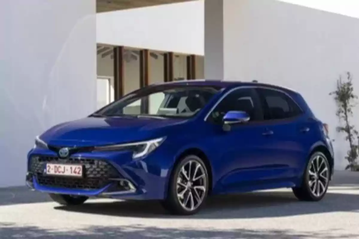 Un coche azul estacionado frente a un edificio blanco.