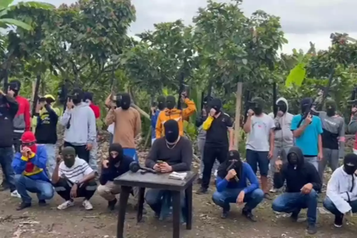 Un grupo de personas enmascaradas y armadas posando en un entorno al aire libre con árboles y vegetación.