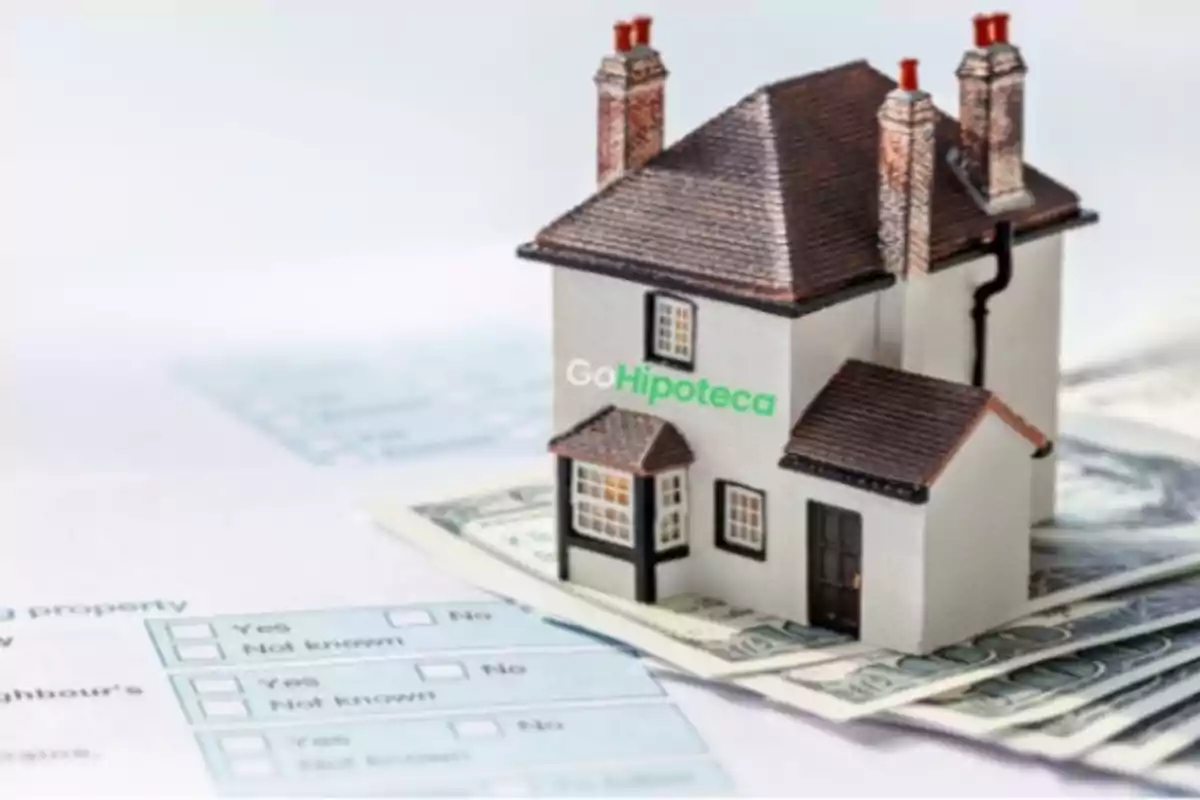 Una casa en miniatura sobre billetes y documentos relacionados con hipotecas.