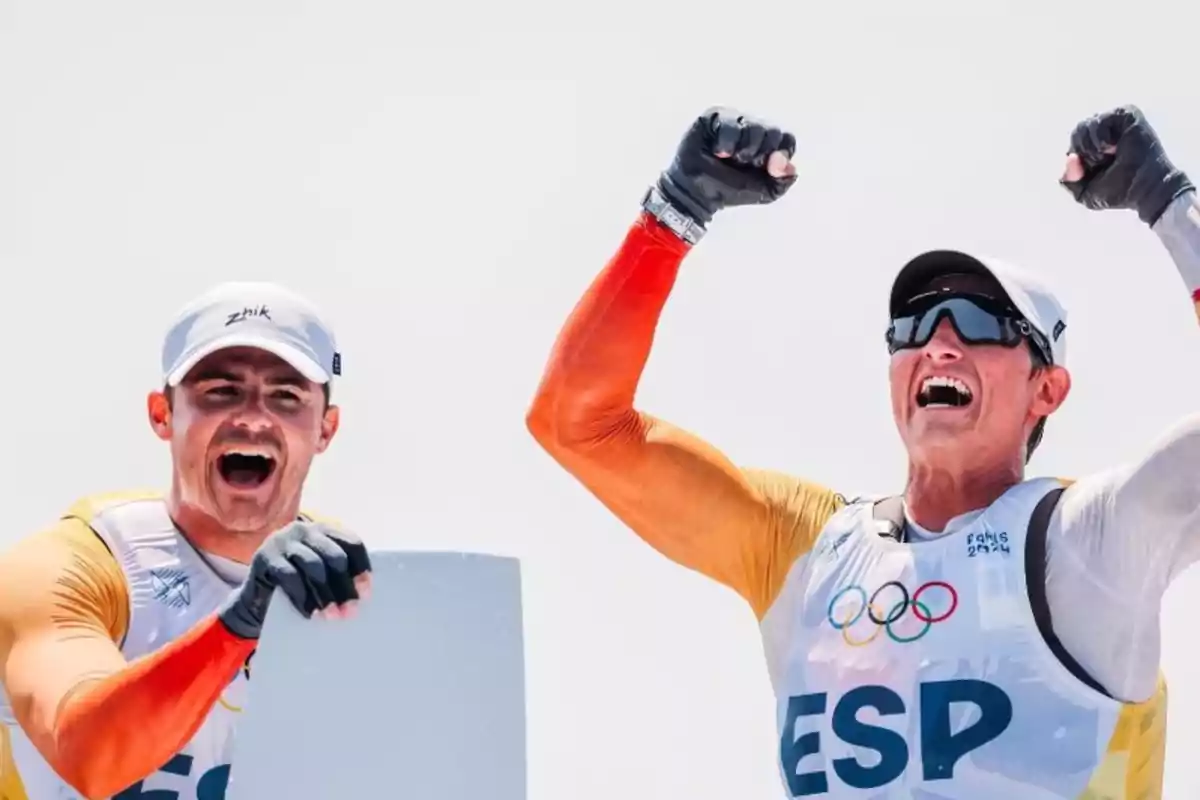 Dos atletas celebrando con entusiasmo mientras llevan uniformes con las letras 