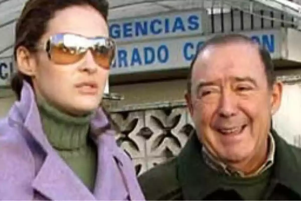 Una mujer con gafas de sol y un hombre sonriente están de pie frente a un edificio con un letrero que dice Una mujer con gafas de sol y un hombre sonriente están de pie frente a un edificio con un letrero que dice
