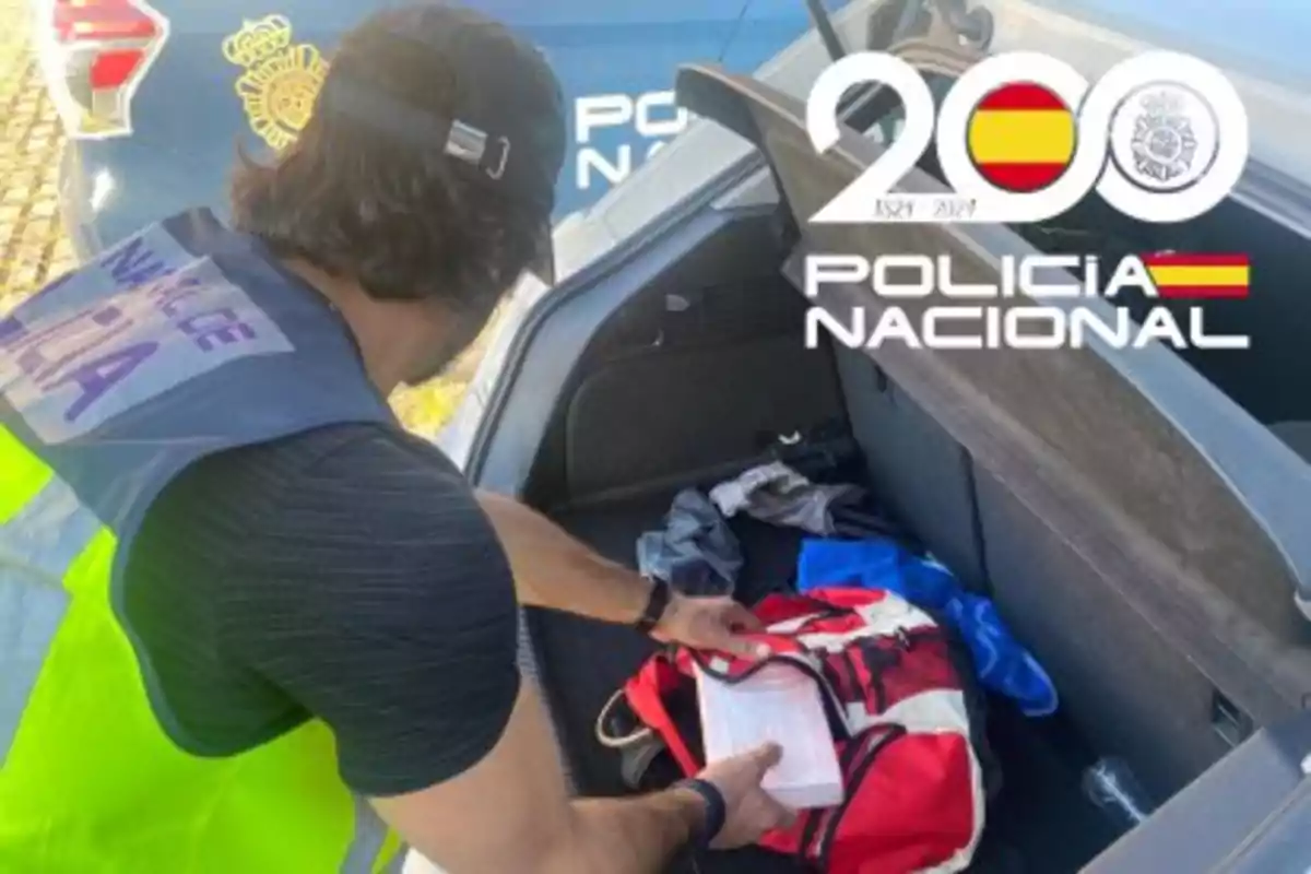 Un agente de la Policía Nacional revisa el contenido de una mochila en el maletero de un coche.