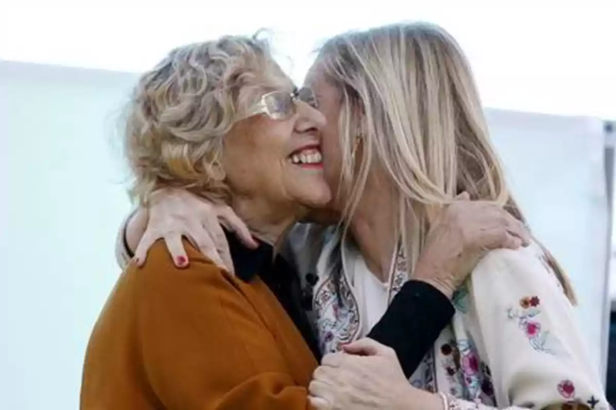 Manuela Carmena y Cristina Cifuentes saludándose con afectuoso abrazo y dos besos