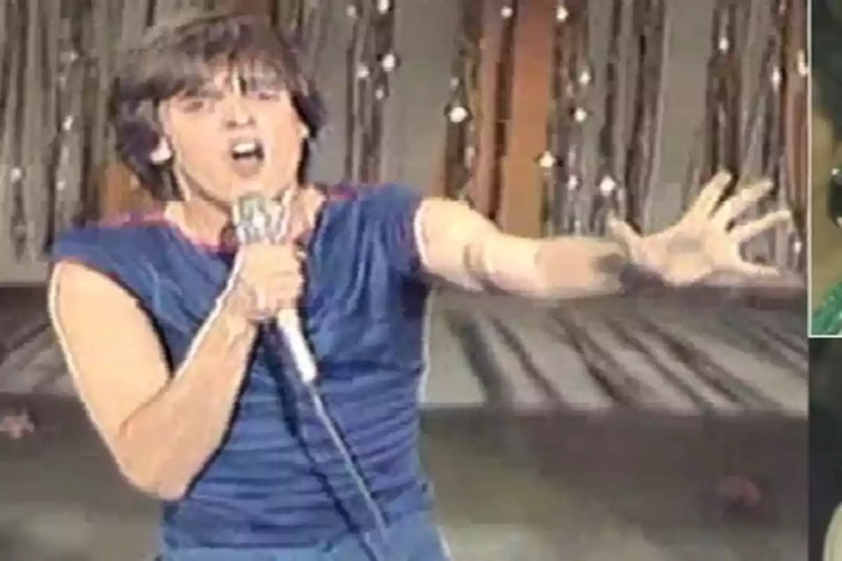 Una persona cantando en un escenario con un micrófono en la mano y el brazo extendido.
