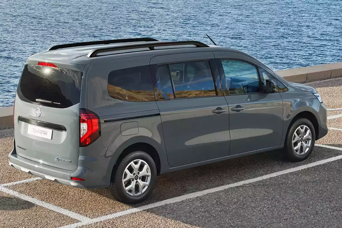 Una furgoneta gris estacionada junto al mar en un aparcamiento.