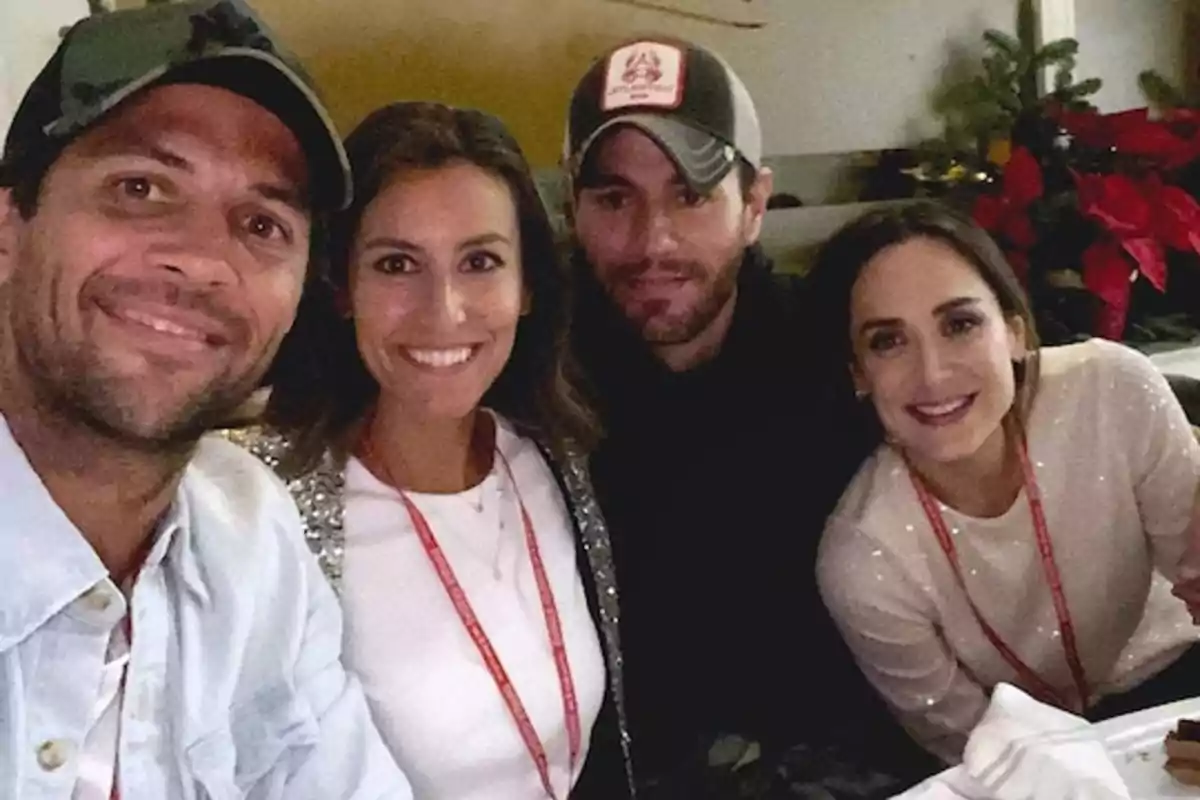 Un grupo de cuatro personas sonríe mientras posan para una foto en un ambiente interior con decoración navideña. Un grupo de cuatro personas sonríe mientras posan para una foto en un ambiente interior con decoración navideña.