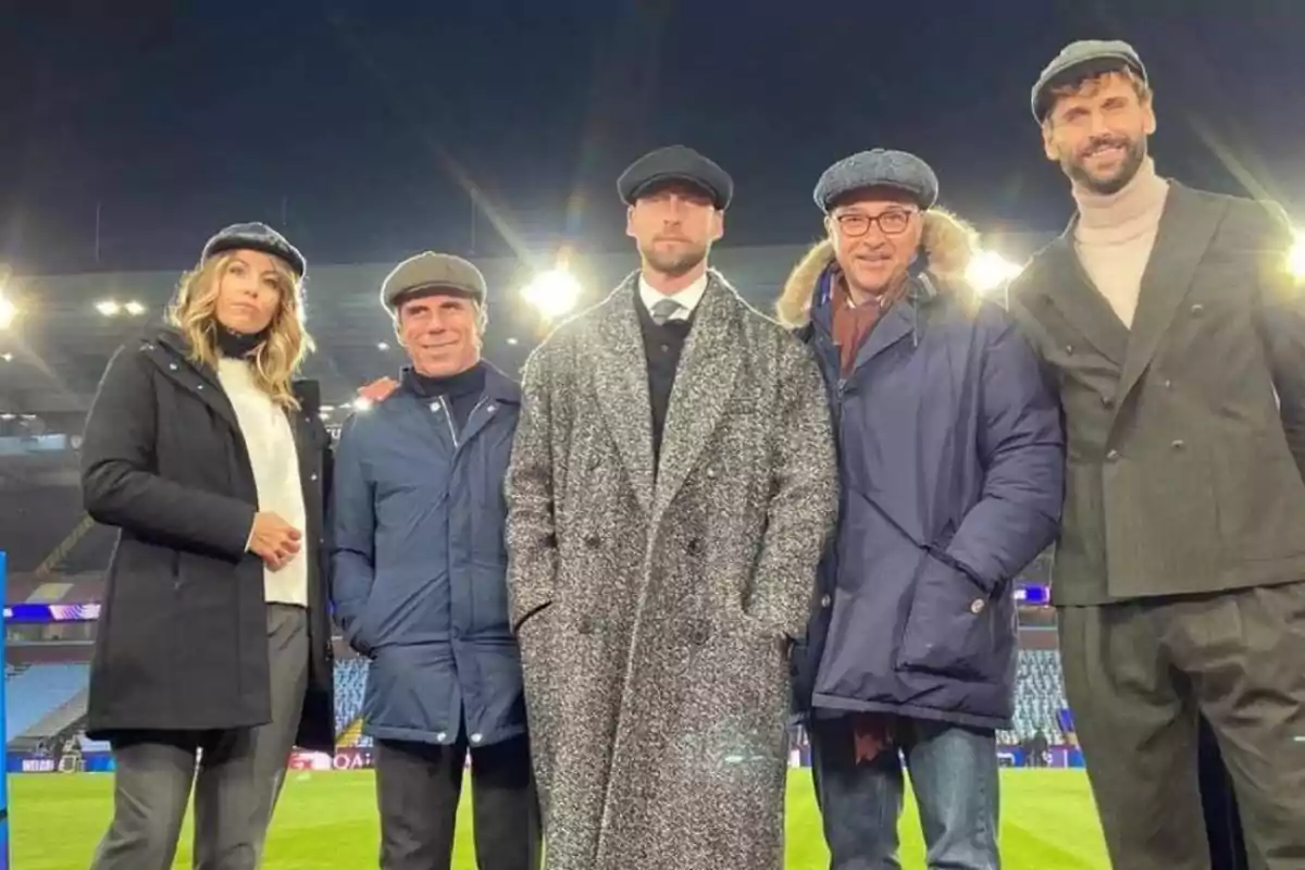 Cinco personas posan en un estadio de fútbol usando boinas y ropa elegante Cinco personas posan en un estadio de fútbol usando boinas y ropa elegante