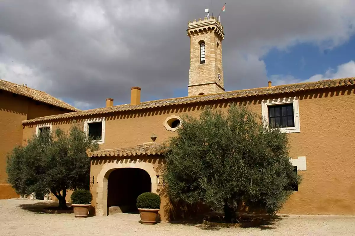 Edificio de estilo rústico con torre de piedra y cielo nublado. Edificio de estilo rústico con torre de piedra y cielo nublado.