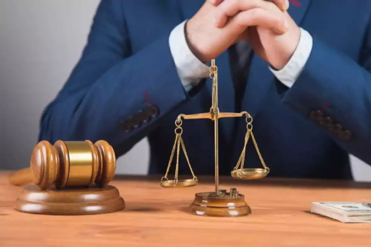 Un juez con un mazo y una balanza de la justicia sobre una mesa de madera.