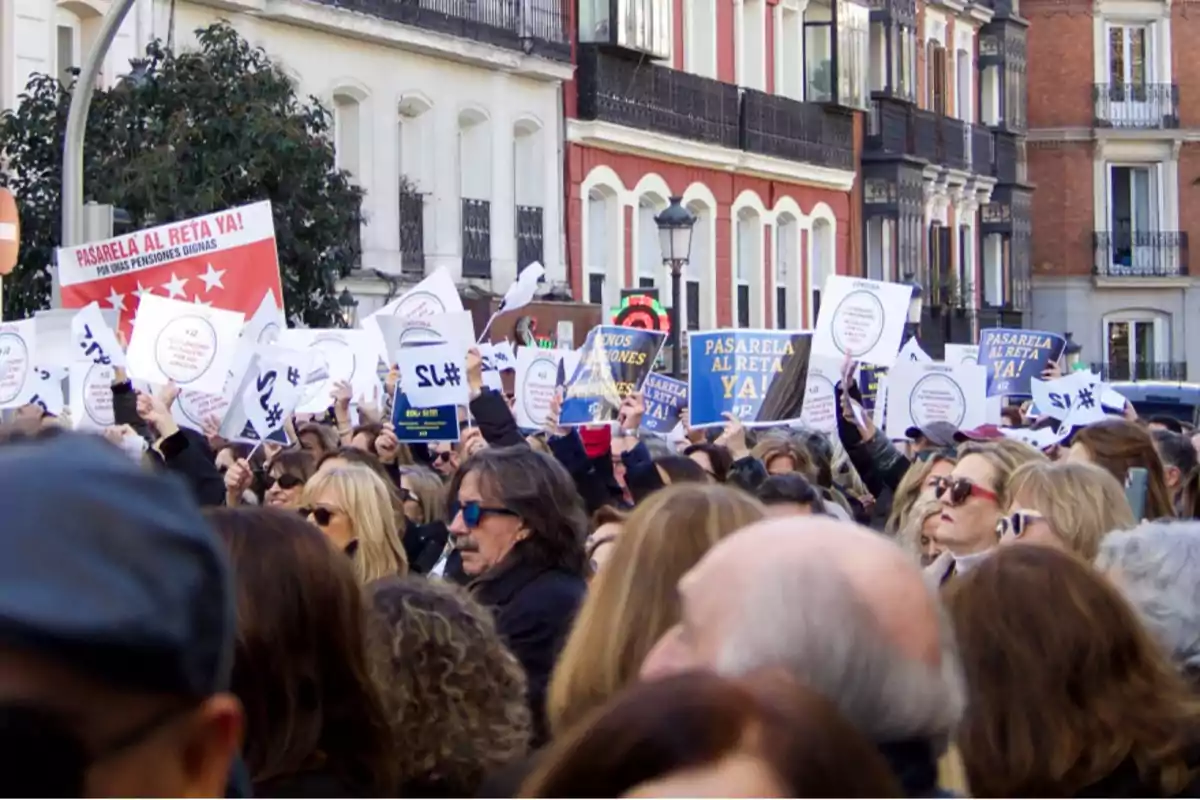 Una multitud de personas se manifiesta en una calle, sosteniendo pancartas y carteles que exigen 