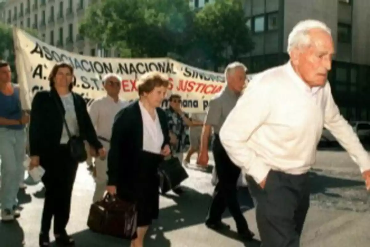 Un grupo de personas mayores participa en una manifestación en la calle, llevando una pancarta de una asociación nacional. Un grupo de personas mayores participa en una manifestación en la calle, llevando una pancarta de una asociación nacional.