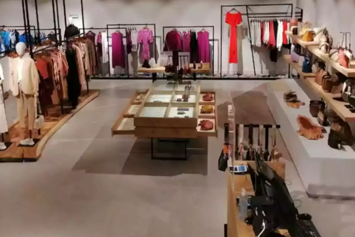 Una tienda de ropa moderna con maniquíes, estantes llenos de prendas coloridas y accesorios organizados en mesas y estanterías.