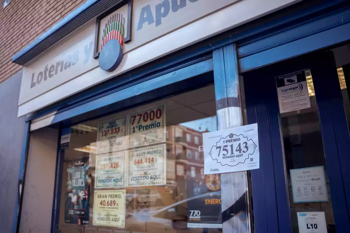 Fachada de una administración de loterías con carteles de premios vendidos.