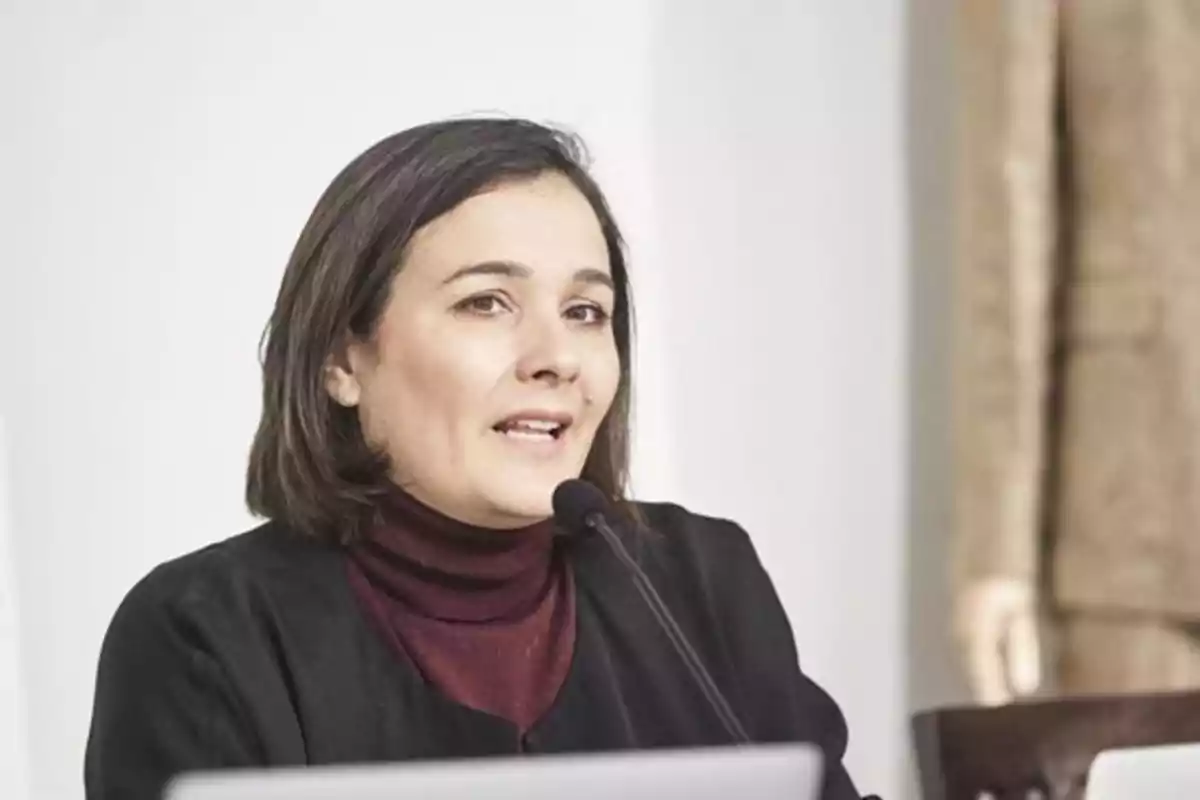 Una mujer hablando en un micrófono durante una presentación o conferencia. Una mujer hablando en un micrófono durante una presentación o conferencia.