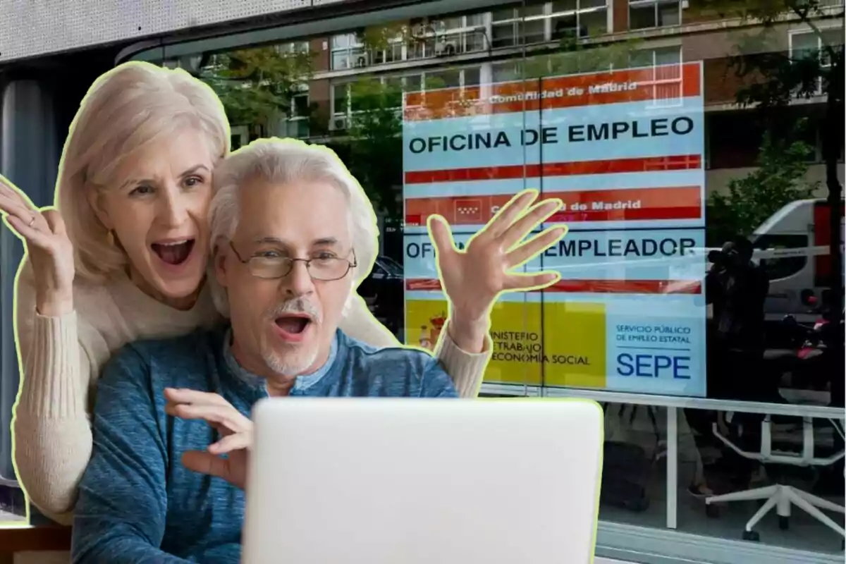 Una pareja de personas mayores se muestra emocionada frente a una computadora, con una oficina de empleo de fondo.