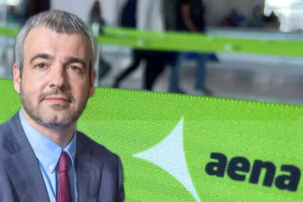 Hombre de traje y corbata frente a una cinta verde con el logo de Aena.