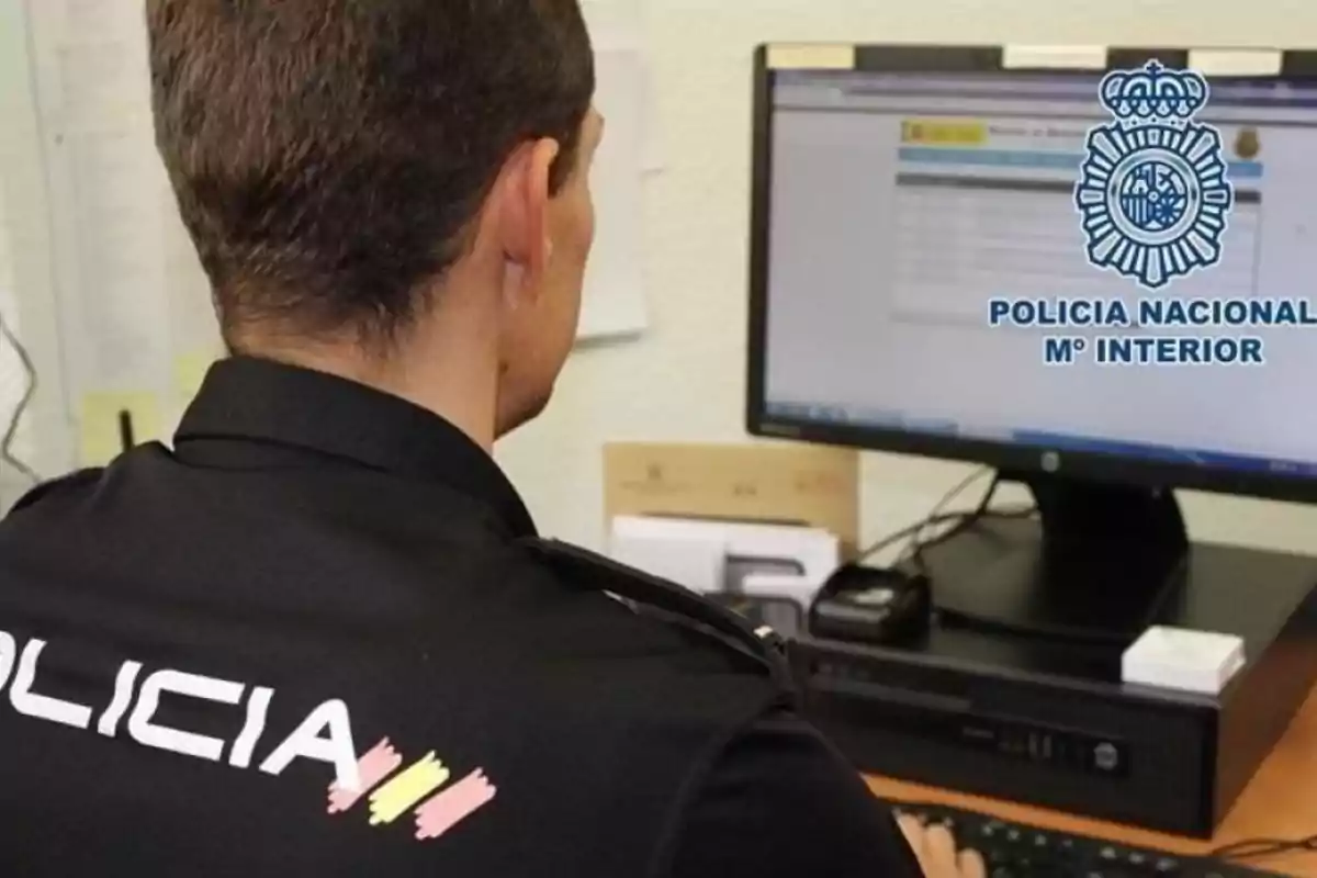 Un policía nacional trabajando en una computadora en una oficina.