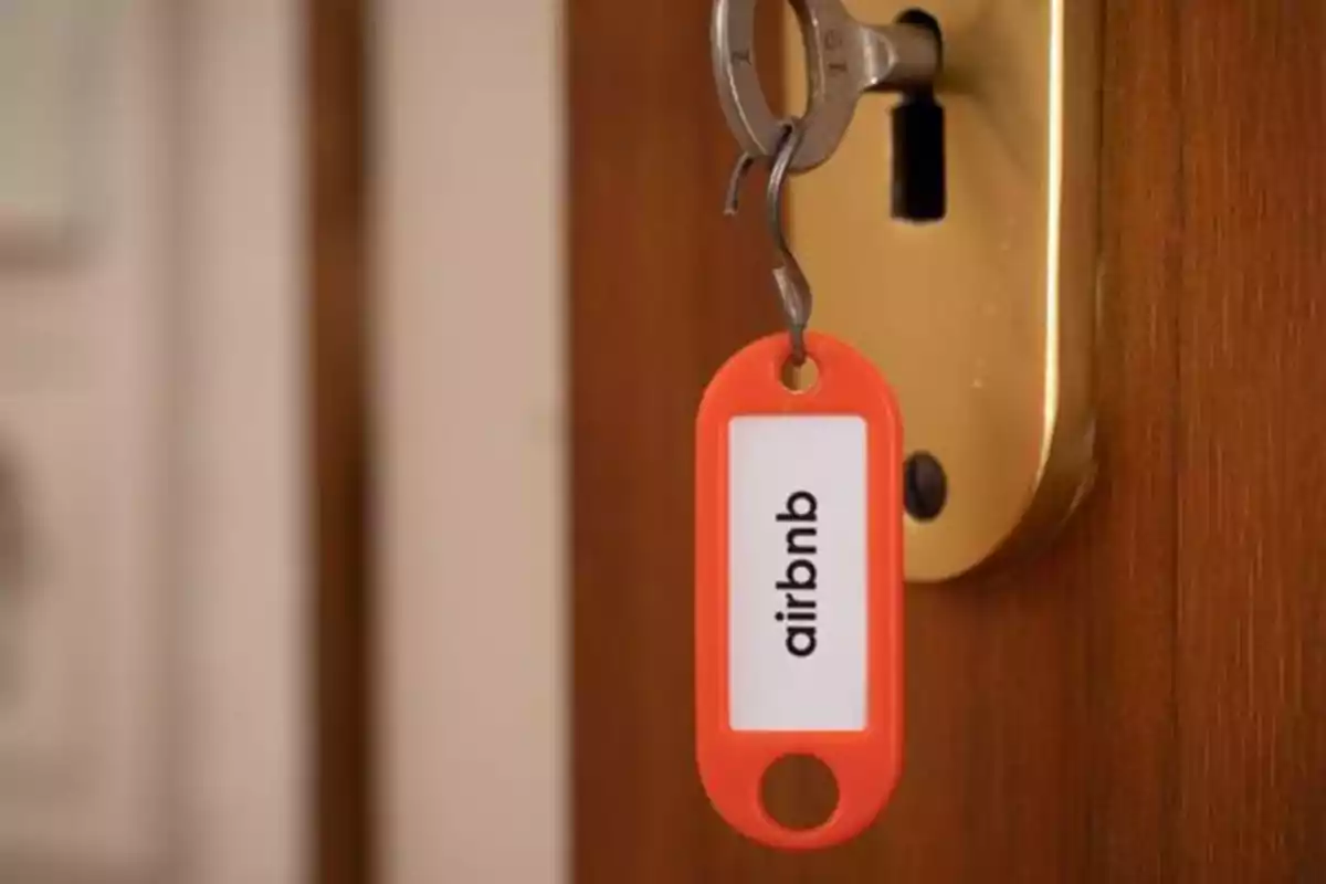 Llave con un llavero rojo de Airbnb insertada en una cerradura dorada.