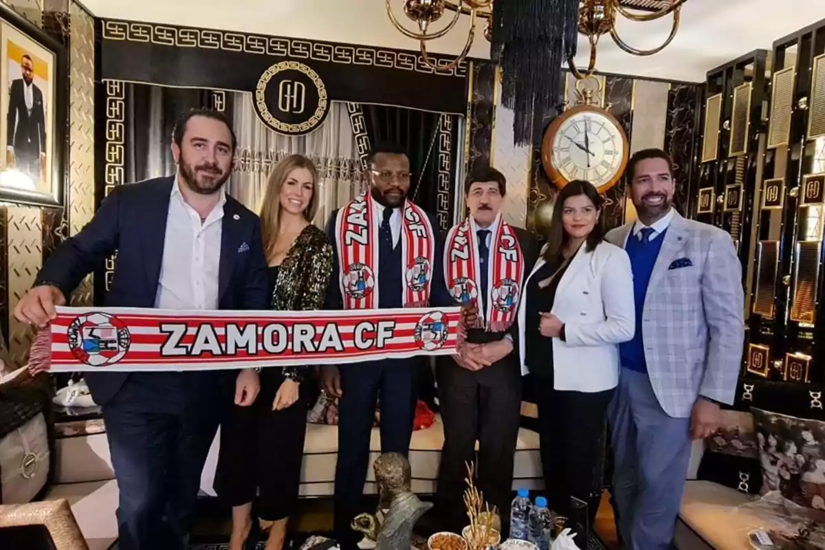 Un grupo de personas posando en una sala elegante con bufandas del Zamora CF.