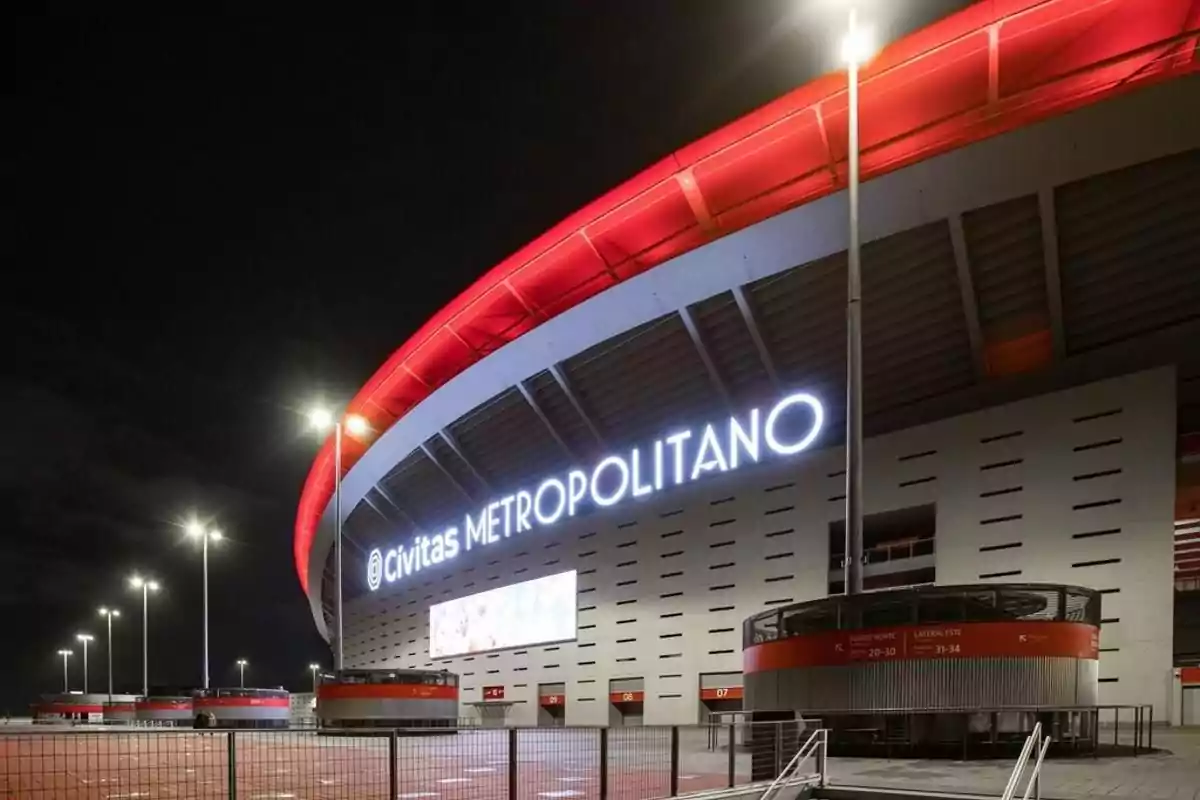 Vista nocturna del estadio Civitas Metropolitano iluminado con luces rojas y blancas.