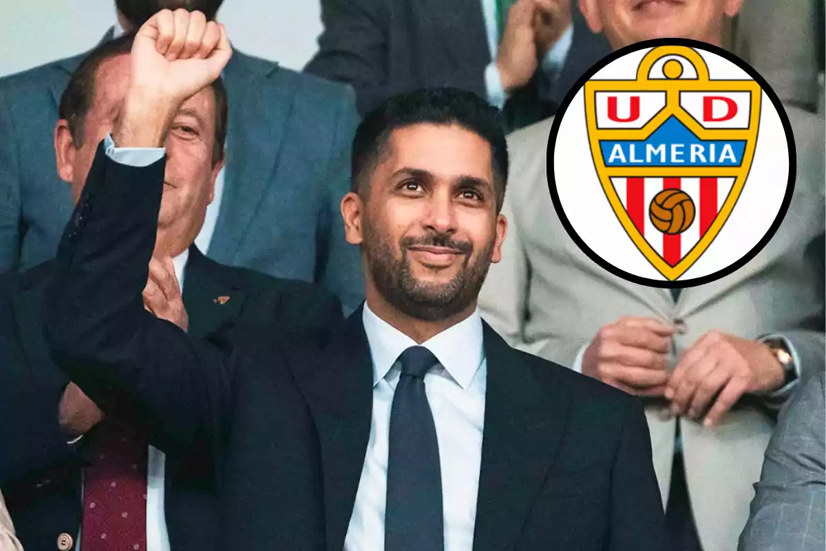 Hombre con traje levantando el brazo en señal de celebración junto al escudo del club de fútbol UD Almería