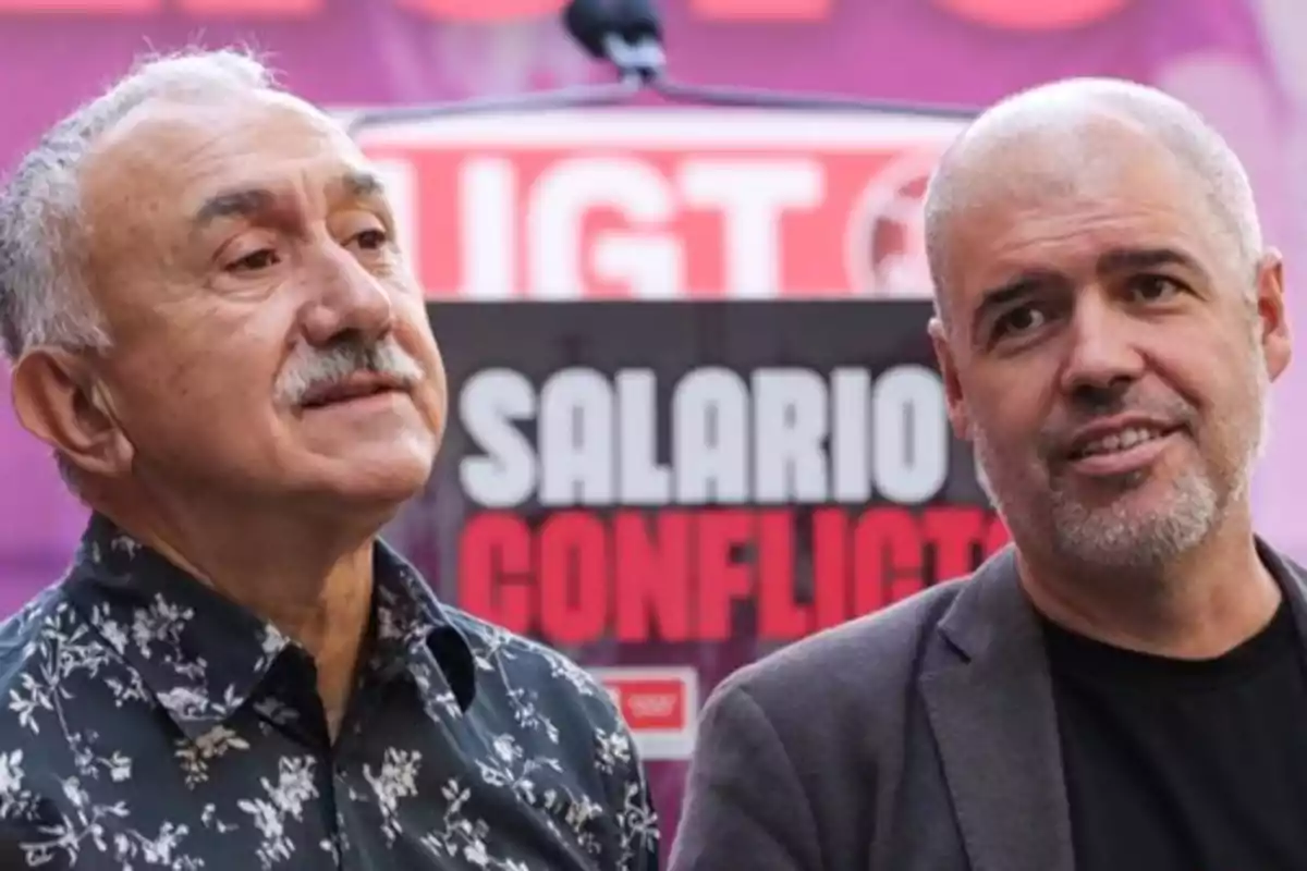 Dos hombres de pie frente a un cartel que dice "Salario Conflicto".