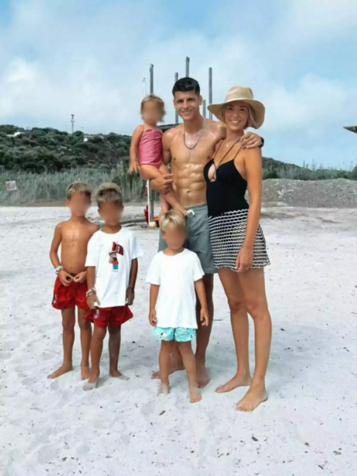 Álvaro Morata y Alice Campello posando en la playa con el mar y vegetación de fondo junto a sus hijos. Post de Álvaro en Instagram el 21 de julio de 2024