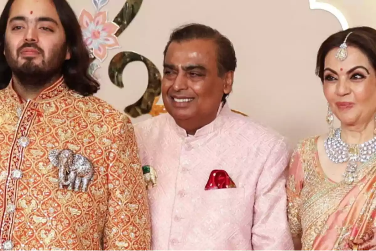 Tres personas vestidas con trajes tradicionales indios posan para una foto, dos hombres y una mujer, todos sonrientes.