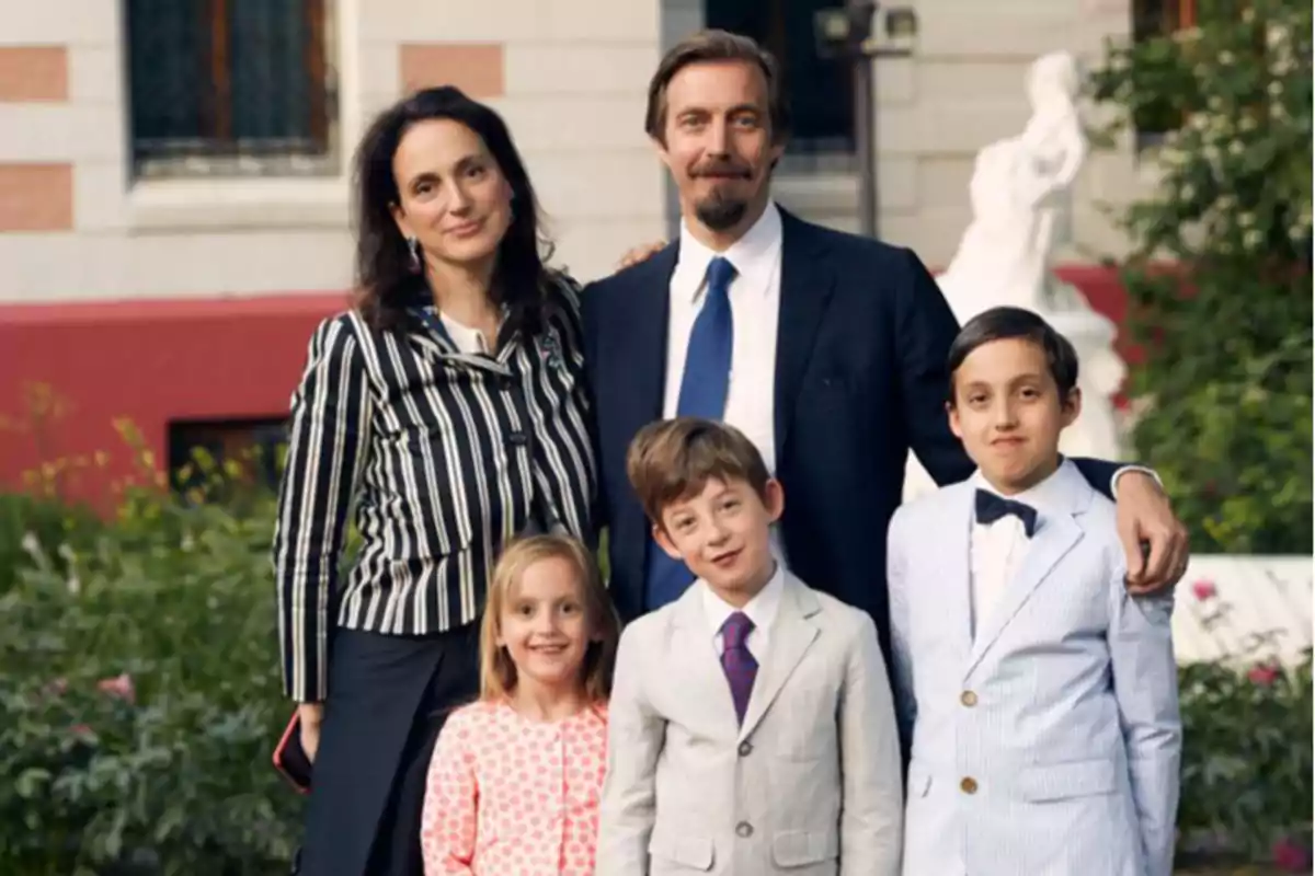Familia posando junta al aire libre con ropa formal y sonriendo frente a un edificio Familia posando junta al aire libre con ropa formal y sonriendo frente a un edificio