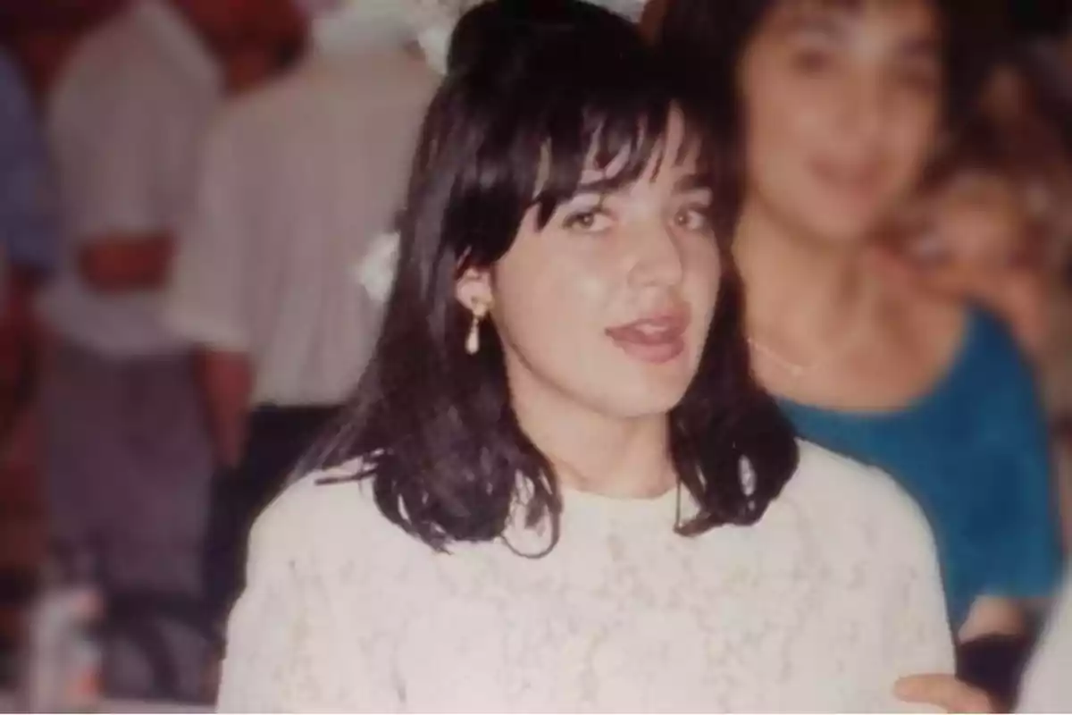 Una mujer con cabello oscuro y vestido blanco en un evento social.