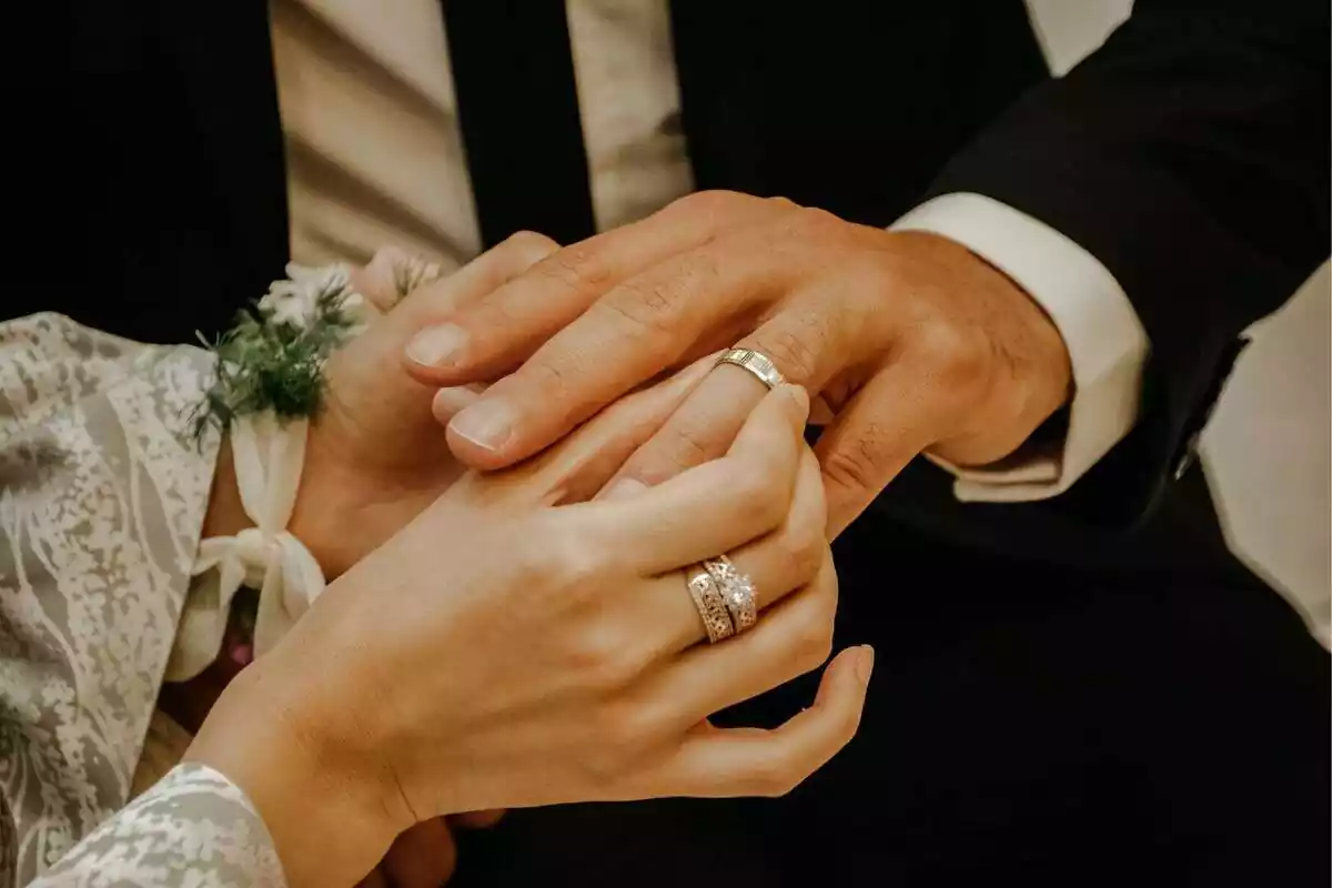 Las manos de una pareja poniéndose el anillo de compromiso en su boda Las manos de una pareja poniéndose el anillo de compromiso en su boda