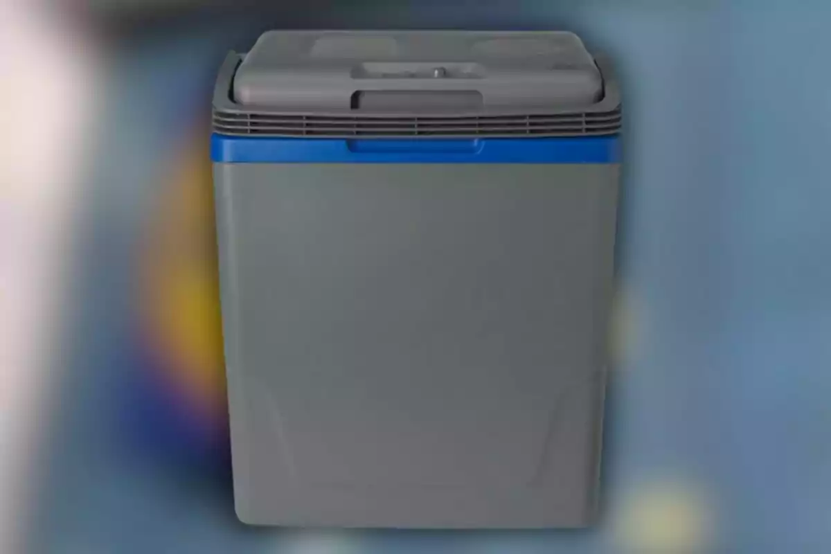 Una nevera portátil gris con tapa superior y detalles azules sobre un fondo desenfocado. Una nevera portátil gris con tapa superior y detalles azules sobre un fondo desenfocado.