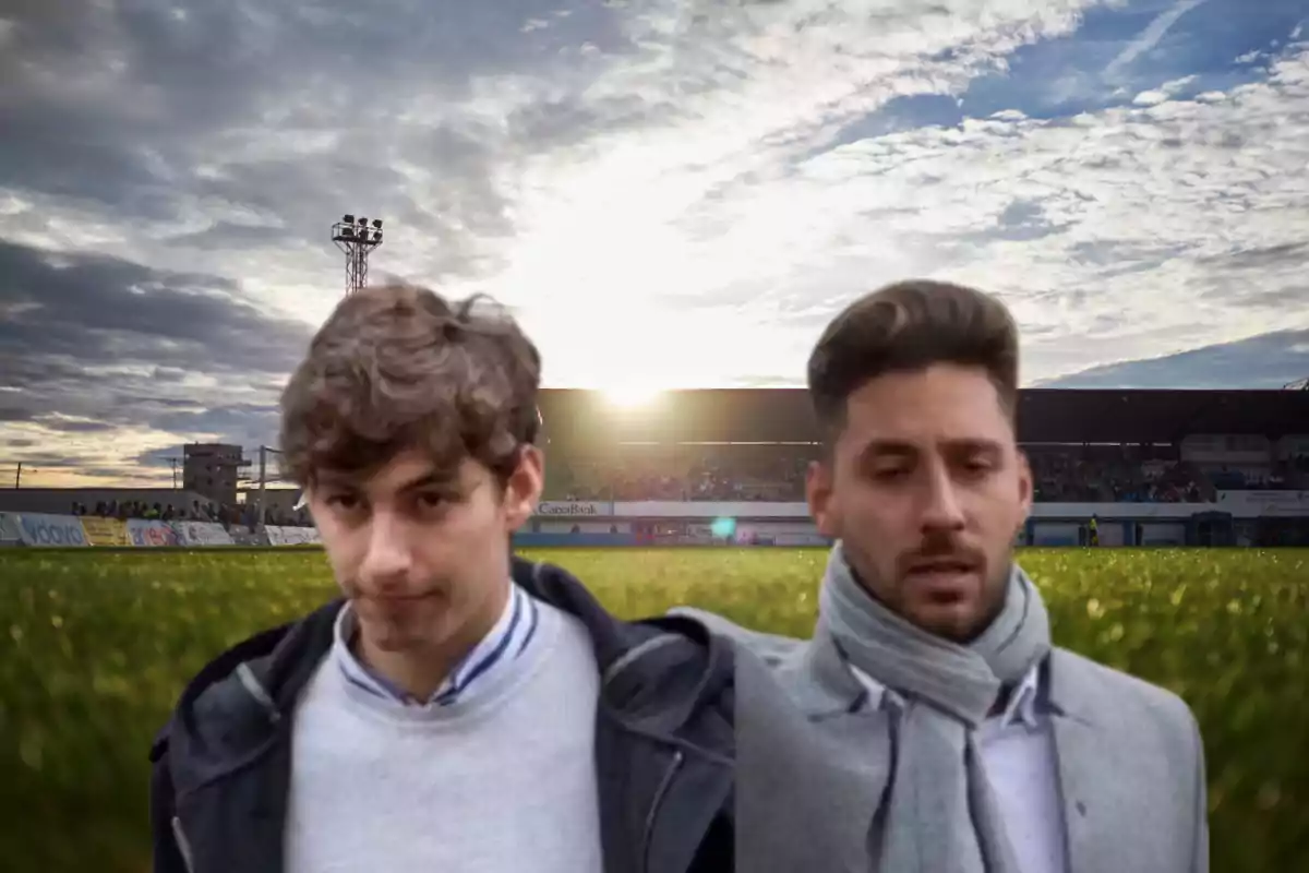 Dos personas en primer plano con un estadio de fondo al atardecer.