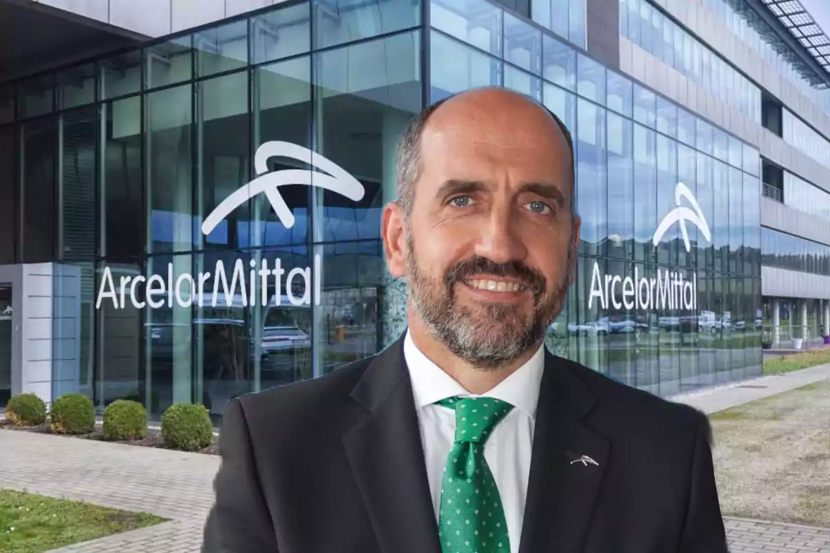 Hombre con traje y corbata verde sonríe frente a un edificio de oficinas con el logo de ArcelorMittal en los ventanales