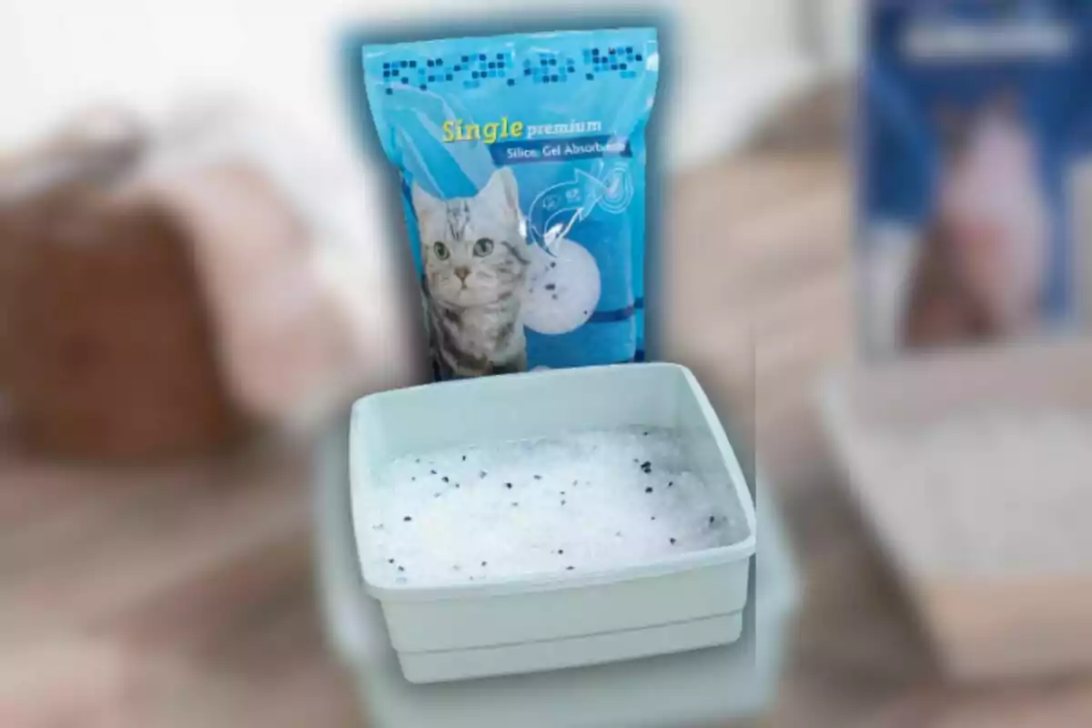 Un paquete de arena para gatos de gel de sílice junto a una bandeja llena del mismo material. Un paquete de arena para gatos de gel de sílice junto a una bandeja llena del mismo material.