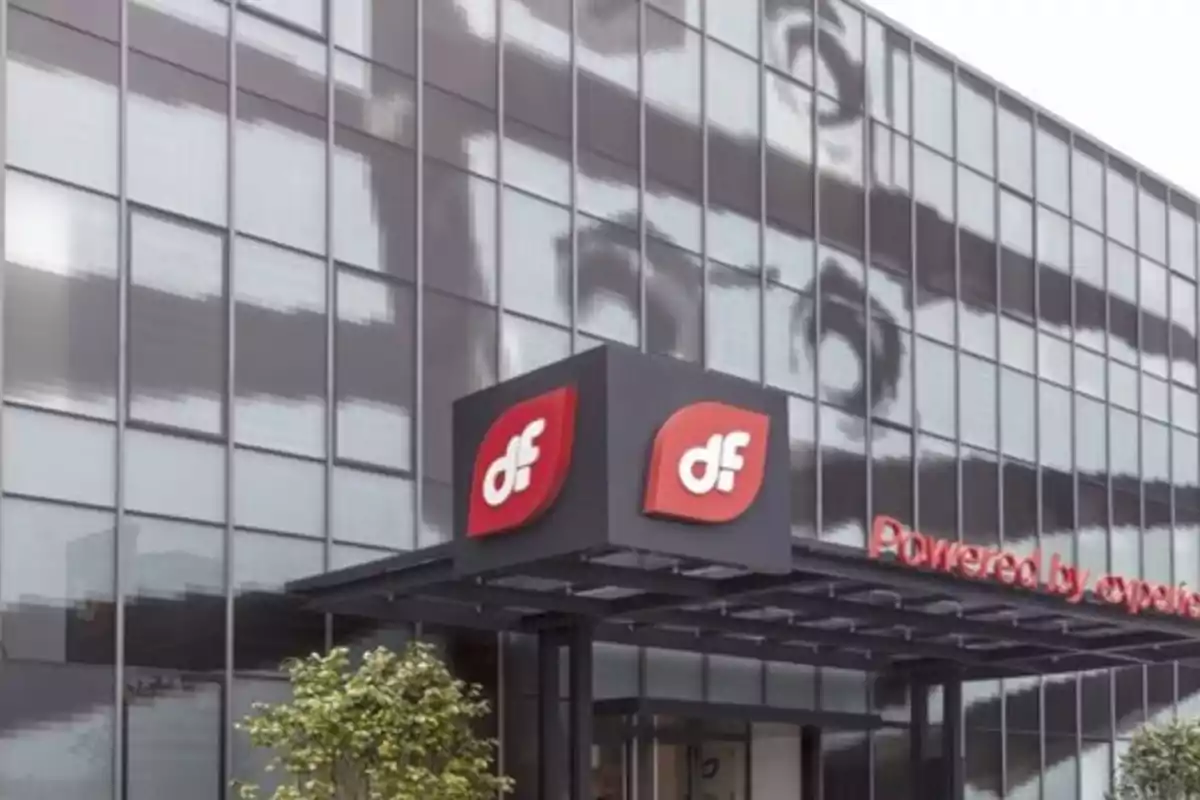 Edificio moderno con fachada de vidrio y un letrero que muestra el logotipo 